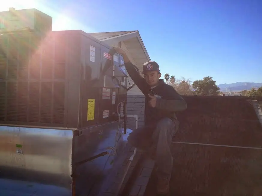 HVAC technician performing AC Tune-Up on a rooftop unit in Centerton