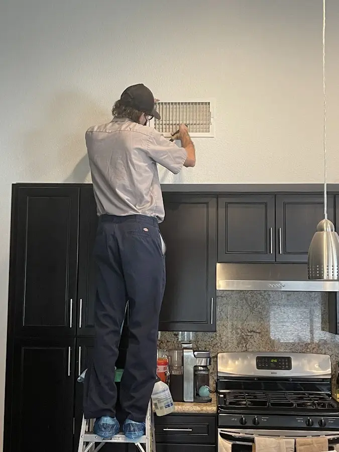Technician inspecting an air vent during HVAC service in Centerton